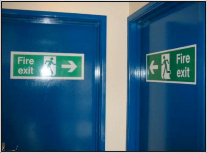 Fire exit signs pointing to a corner